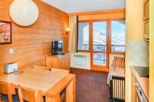 a dining room with a table and a television at Residence La Marelle et Le Rami - maeva Home in Les Coches