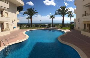 a swimming pool in the middle of a building with palm trees at COSTA DAURADA APARTAMENTS - Colibri Beach in Cambrils