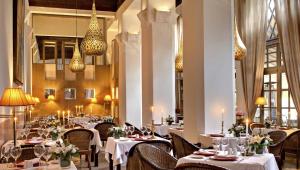 un restaurante con mesas y sillas blancas y lámparas de araña en Les Jardins De La Médina, en Marrakech