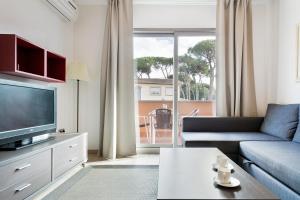 a living room with a couch and a tv at Aparthotel Bardon in Castelldefels