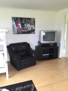 uma sala de estar com um sofá de couro preto e uma televisão em Rolösa em Hjo