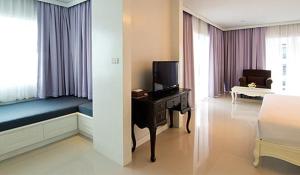 a hotel room with a bed and a desk with a television at Welcome World Beach Resort & Spa in Pattaya South