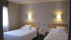 una camera d'albergo con due letti e due luci di Hotel Migal a Cue