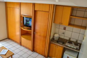 a small kitchen with wooden cabinets and a television at Hotel Flat Classic in Fortaleza