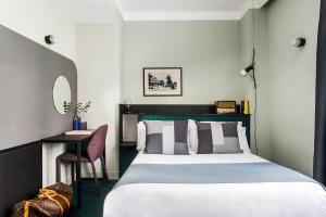 a bedroom with a bed, desk and a lamp at Hôtel les Cigales in Nice