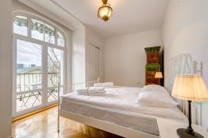 a white bedroom with a bed and a large window at Dom & House - Apartment Fiszera Sopot in Sopot