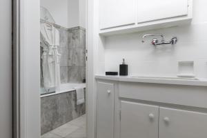 a white bathroom with a sink and a shower at The Parliament Studio in Athens
