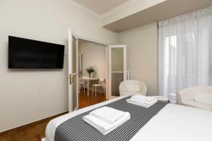 a white bedroom with a bed and a flat screen tv at The Parliament Studio in Athens