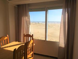 a bedroom with a view of the beach from a window at Apartamentos Calypso in Punta Umbría