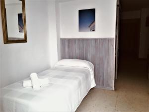 a bedroom with a white bed and a mirror at Apartamentos Calypso in Punta Umbría