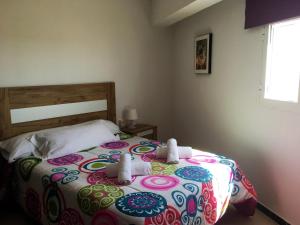 a bedroom with a bed with a colorful bedspread at Apartamentos Calypso in Punta Umbría