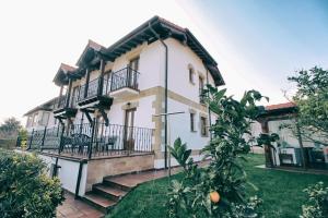 a white house with a balcony and a yard at Apartamentos La Fuente de Enmedio in Suances