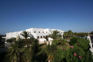a large white building with palm trees in front of it at Residence Club Barbara in Ostuni