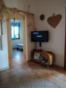 sala de estar con TV de pantalla plana en la pared en Villino Asfodeli, en San Teodoro