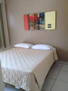 a bed in a bedroom with a painting on the wall at Hotel Portal do Éden in Sorocaba