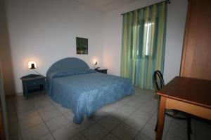 a bedroom with a bed and a desk and a window at Residence Club Barbara in Ostuni