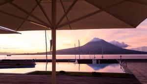 a view of a mountain from a dock with an umbrella at Azoris Faial Garden – Resort Hotel in Horta
