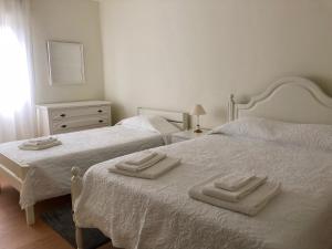 ポンタ・デルガダにあるApartamento Canto da Maiaのベッドルーム1室(ベッド2台、タオル付)