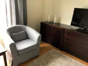 uma sala de estar com uma cadeira e uma televisão em Apartamento Canto da Maia em Ponta Delgada