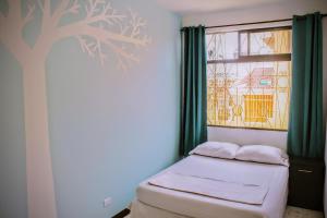 a small bedroom with a tree mural on the wall at StrayCat in San José