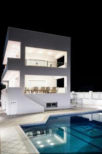 a building with a swimming pool in front of a house at Villa d'Irene-near athens airport , 200 meters from the beach davis in Artemida