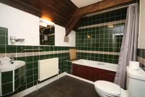 a green tiled bathroom with a toilet and a sink at Three Wheat Heads in Thropton