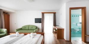 a hotel room with two beds and a green couch at Hotel Garni Planaces in Ortisei