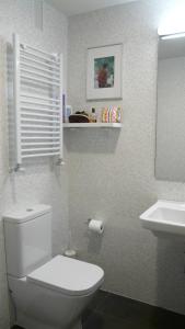 La salle de bains est pourvue de toilettes blanches et d'un lavabo. dans l'établissement Apartamento primera línea de playa, à Benicàssim