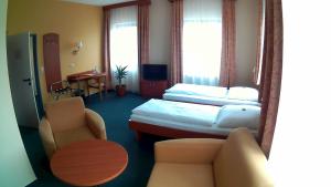 Habitación de hotel con 2 camas, sofá y silla en Hotel Christinenhof garni - Bed & Breakfast, en Gadebusch