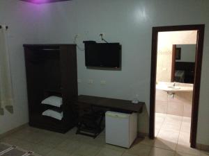 a bathroom with a sink and a television on the wall at Muiraquitã Hotel in Ourilândia do Norte
