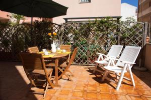 einen Tisch, Stühle und einen Regenschirm auf einer Terrasse in der Unterkunft Marisal Accommodation in Alghero