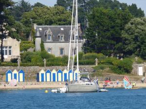 a sail boat in the water in front of a house at Le Jardin Fleuri in Ploemel