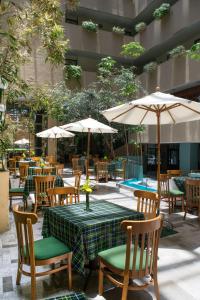 un patio al aire libre con mesas, sillas y sombrillas en Hotel San Francisco, en Toluca