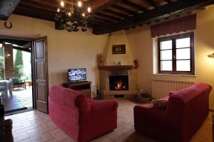 皮恩扎的住宿－Podere Cacchini，客厅配有两把椅子和壁炉