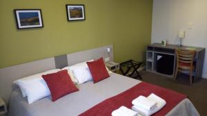 - une chambre dotée d'un grand lit avec des oreillers rouges et blancs dans l'établissement Estepa Hotel, à General Roca