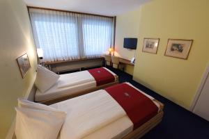a hotel room with two beds and a window at Hotel Dufour in Biel