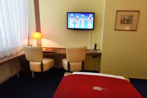 a hotel room with a desk and a television on the wall at Hotel Dufour in Biel