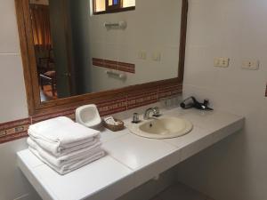 a bathroom with a sink and a mirror and towels at Hotel Pisonay Pueblo in Urubamba