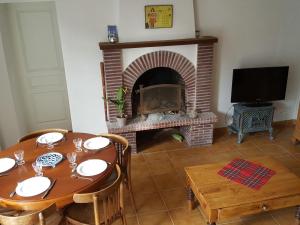 a dining room with a table and a fireplace at Le Petit Lustucru in Saint-Martin-des-Champs