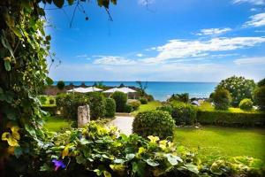 a garden with bushes and flowers and the ocean at Hotel Palazzo Ducale in Diamante