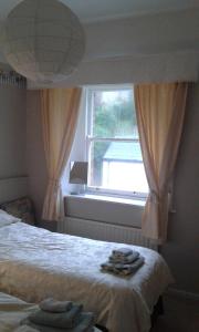 a bedroom with a window with towels on the bed at Coastguard Cottage in Newcastle