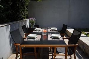 une table avec des chaises et une table noire, des assiettes et des bols dans l'établissement Duplex Pombal, à Saint-Jacques-de-Compostelle