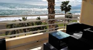 a balcony with a view of the ocean and palm trees at APARTAMENTO FRENTE AL MAR,PRIMERA LINEA in Rincón de la Victoria