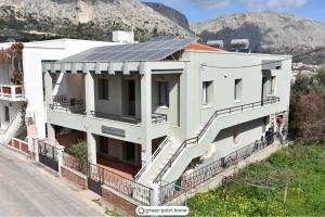 un bâtiment blanc avec des panneaux solaires sur son toit dans l'établissement Green Point Home Chios, à Vrontádos