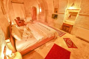 a bedroom with a bed and a chair and a fireplace at Mosaic Cave Hotel in Göreme