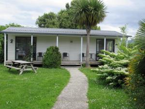 a white house with a picnic table in the yard at White Elephant Accomodation in Motueka