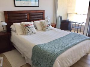 1 dormitorio con 1 cama blanca grande con almohadas en Departamento Costa de Montemar, en Concón