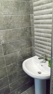a bathroom with a white sink and a tile wall at Number 4 in Derry Londonderry