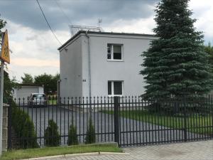 una casa bianca con una recinzione e un albero di Amelia a Schodnia Stara