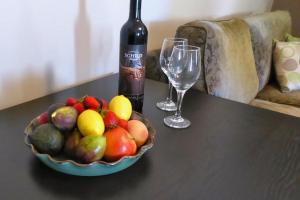 a bowl of fruit and a bottle of wine on a table at Penzance Cottage in Adelaide